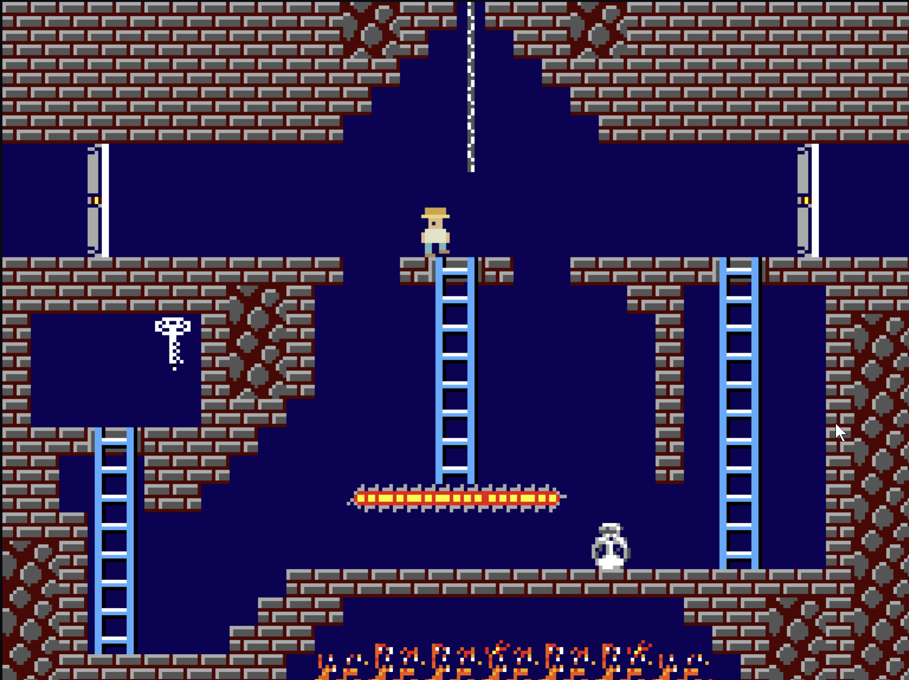 Ruins of Xol gameplay: the explorer stands above a ladder in a brick temple chamber, with a key, locked doors, a laser barrier, a rolling skull and a fire pit below